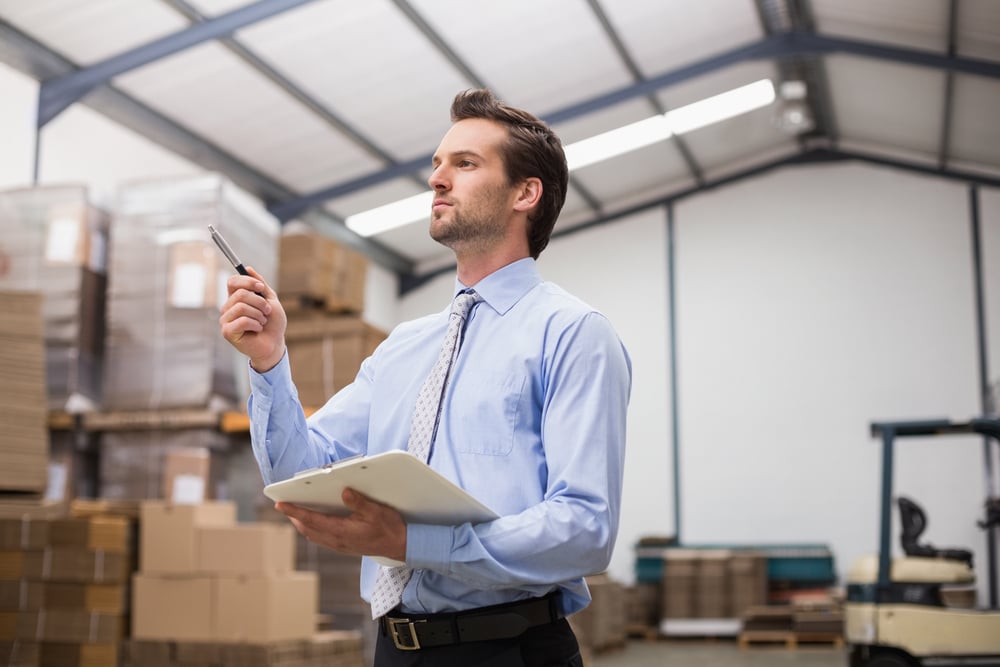 Side view of manager holding clipboard in the warehouse Side view of manager holding clipboard in the warehouse